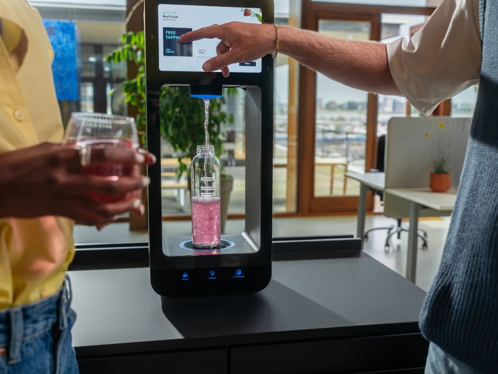 Aquablu water dispenser Two people using Aquablu touchscreen water dispenser to fill a bottle with flavoured water